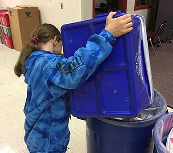 Alki student emptying recycling bin