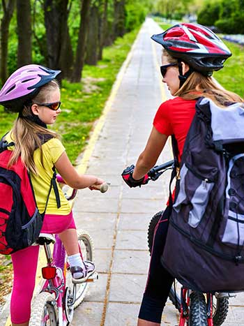 teen and younger girl riding bikes to school